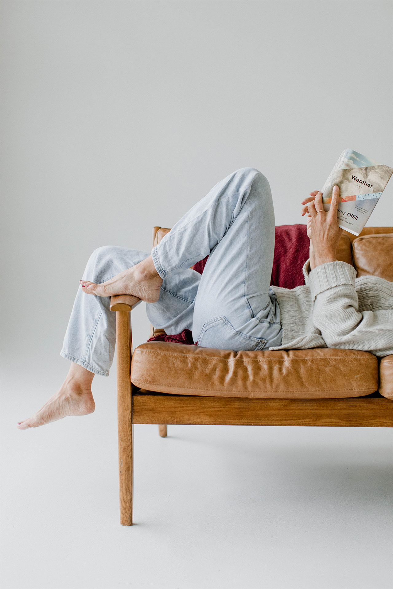Teen cozied up with books on couch