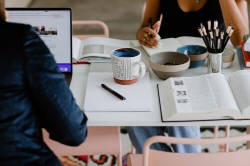 Family planning summer college visits with a notebook and campus map on a warm, neutral desk."
